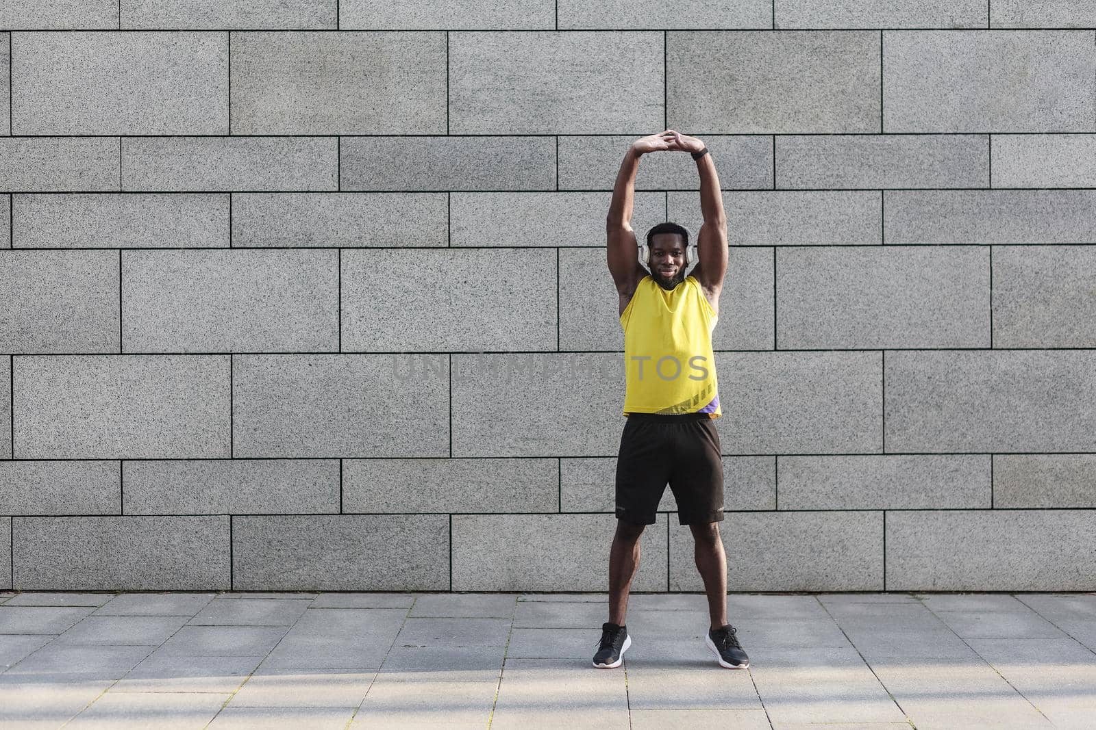 Male runner in yellow sportswear stretching before doing morning workout by Khosro1