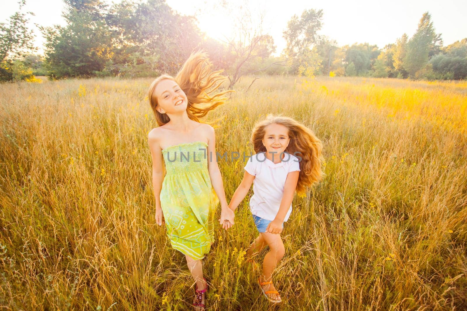 two sisters enjoying together at summertime. jumping and running in the park on sunset and happy