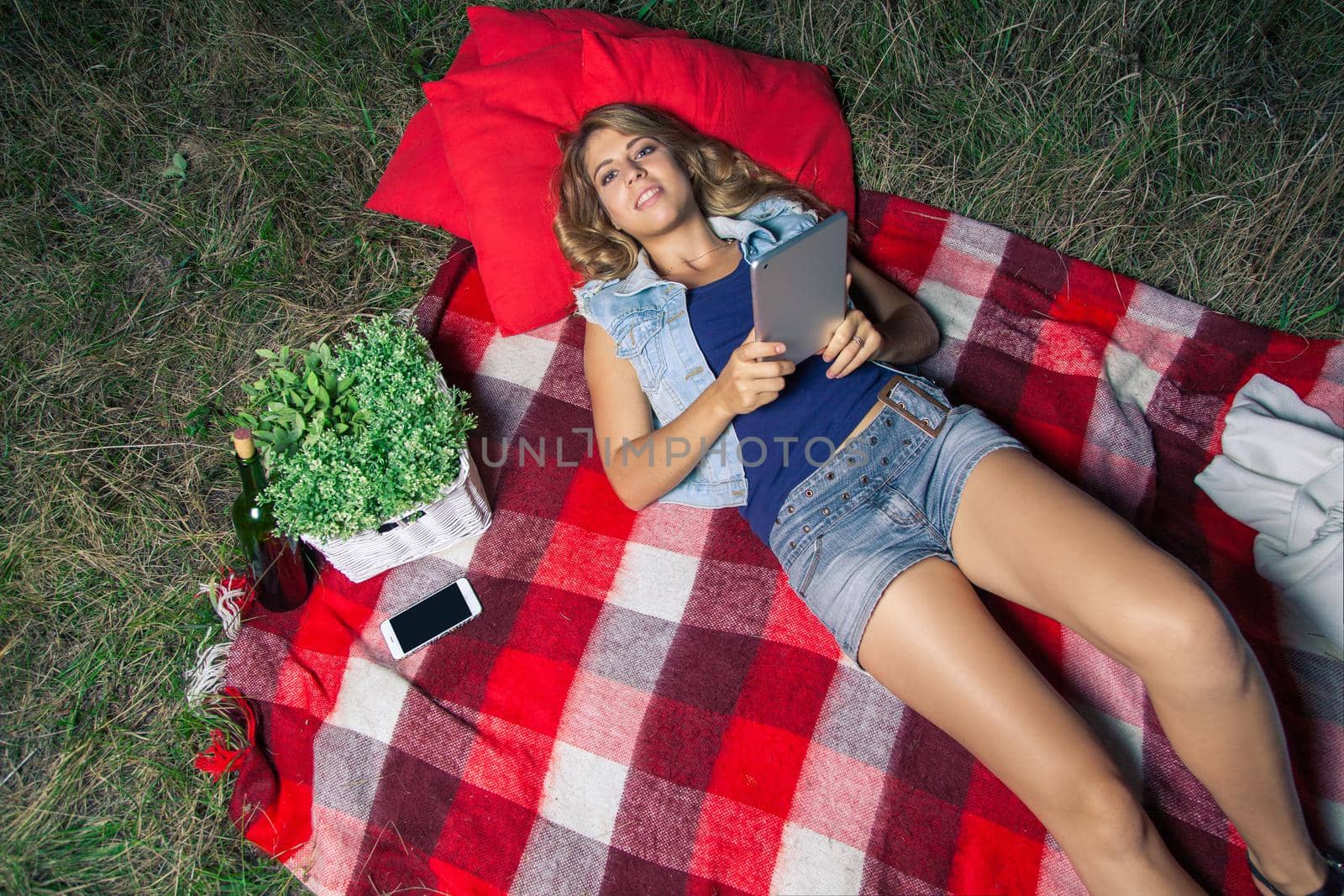 Portrait of woman lie down and holding tablet on summertime outdoor