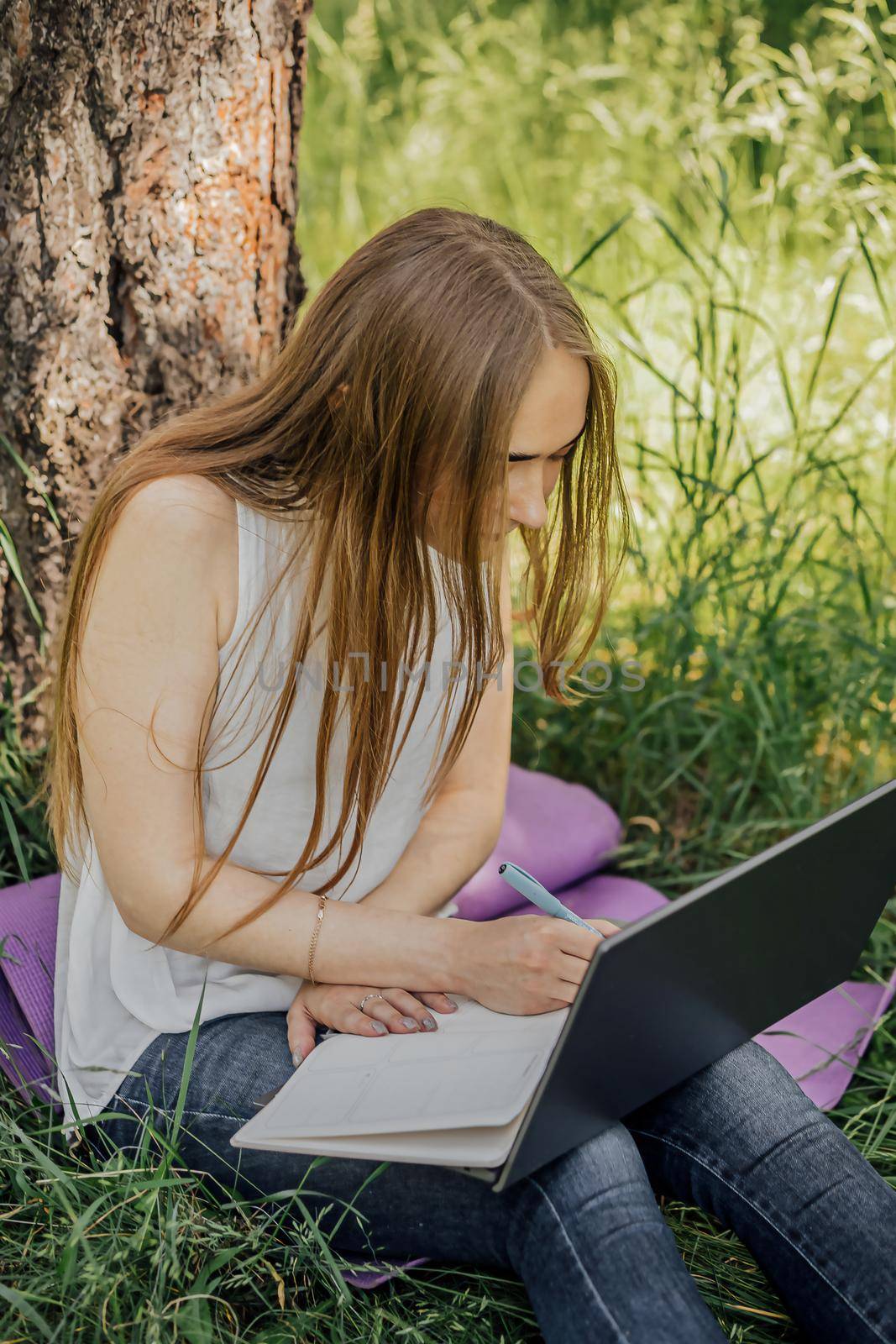 the girl sits on the grass and uses a laptop. Education, lifestyle, technology concept, outdoor learning concept by Anyatachka