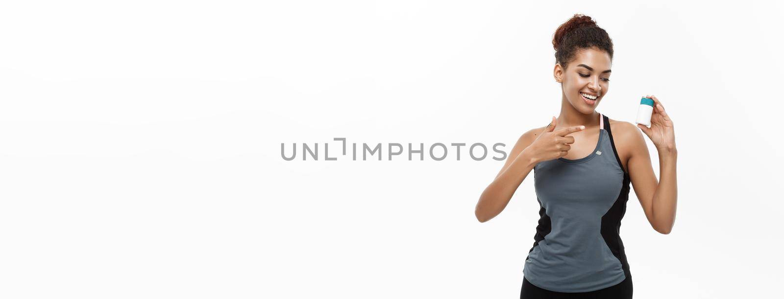 Healthy and healthcare concept - portrait of beautiful sporty African American holding bottle of supplementary bottle. Isolated on white studio background