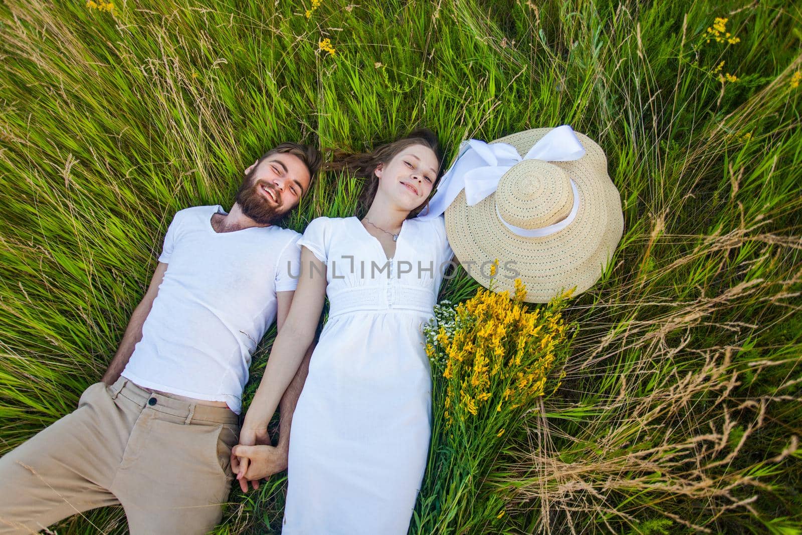 Happy young relaxed couple in love laying down on the grass overhead. by Khosro1
