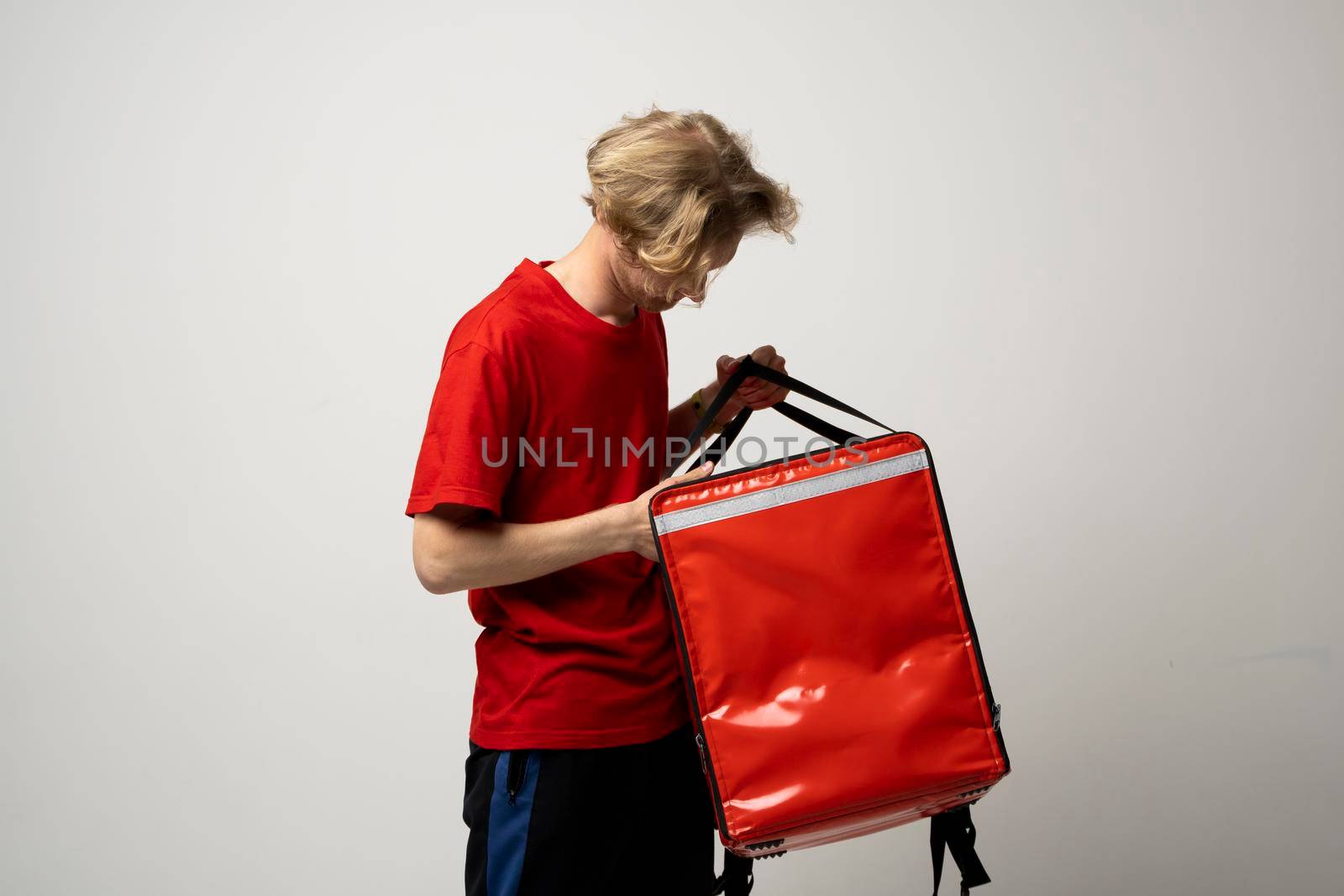 Young courier with thermo bag on white background. Food delivery service. by vovsht