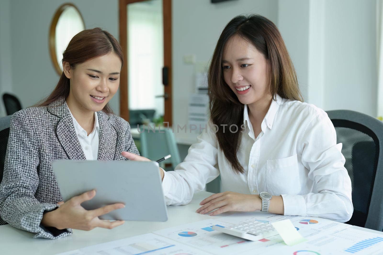 Portrait of a young Asian businesswoman using tablet computers to plan marketing strategies and invest to profit from customers.
