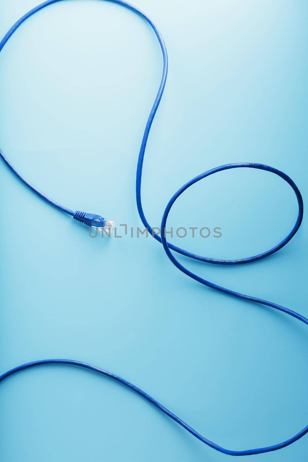 A coil of an Internet network cable for data transmission on a blue background. Patch cord for LAN cable.