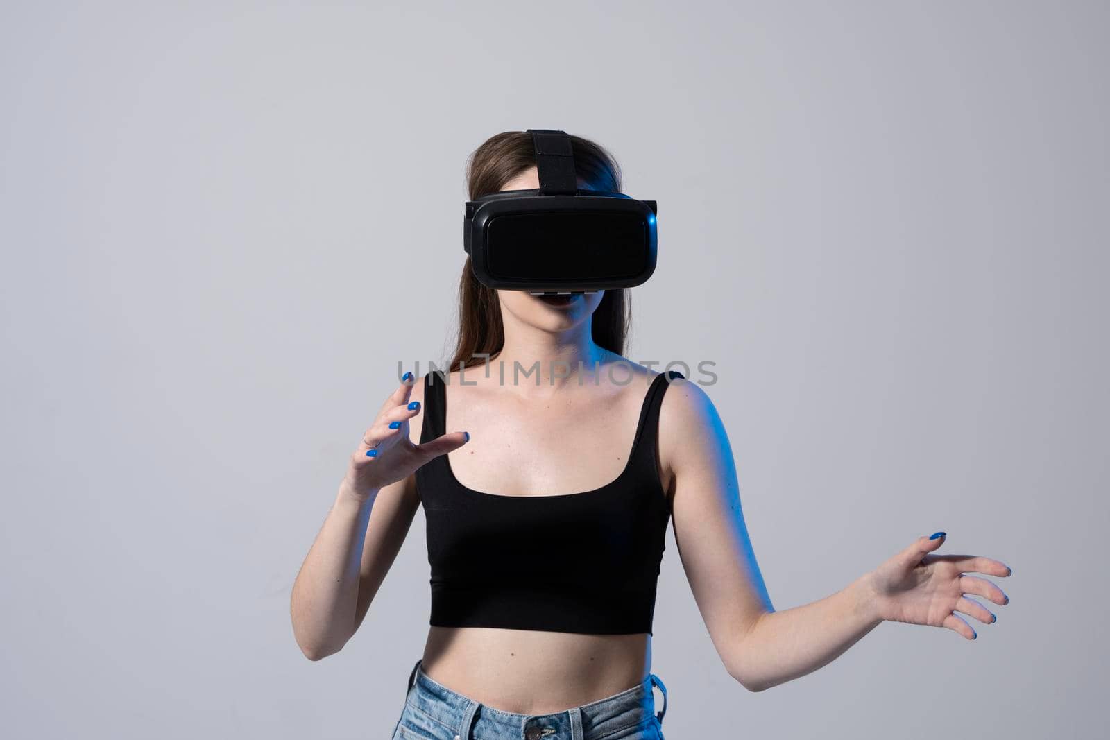 Woman using virtual reality glasses in a studio. Business woman wearing VR goggles and interacts with cyberspace using swipe and stretching gestures. by vovsht