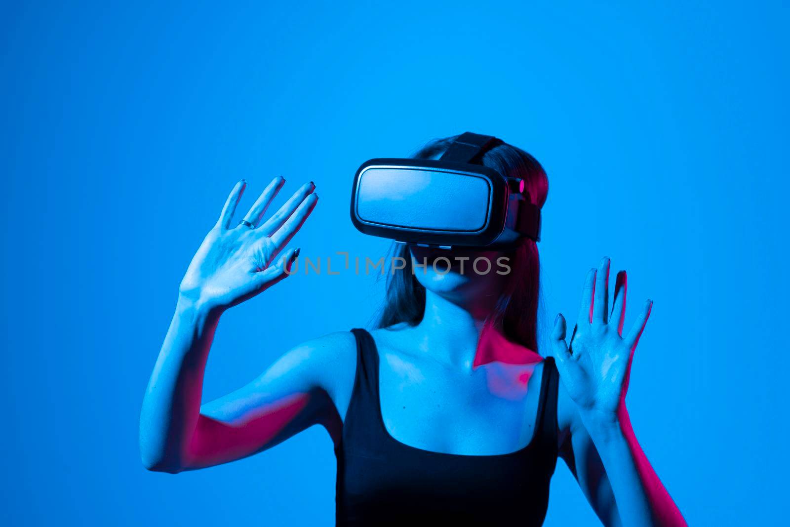 Young woman working in VR goggles on a grey background. Modern architect using virtual reality glasses at workplace. Designer working in augmented reality vr studio