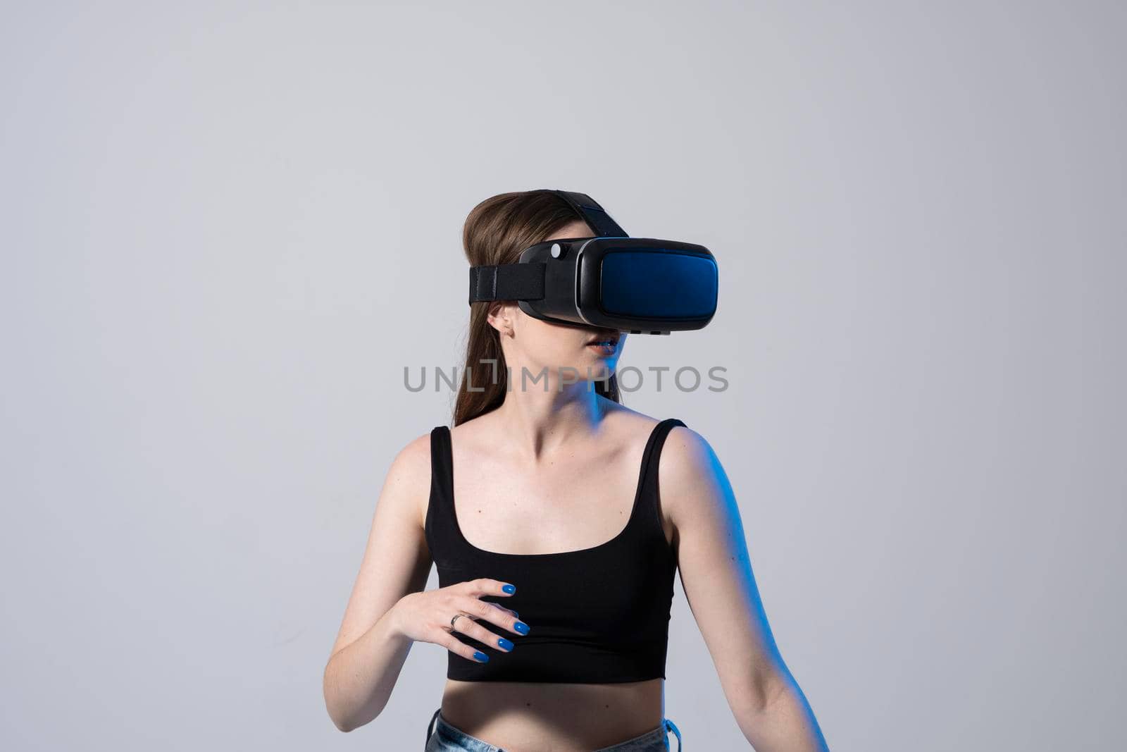 Young attractive brunette woman wearing VR goggles and enjoying amazing experience playing and having fun in virtual reality video game