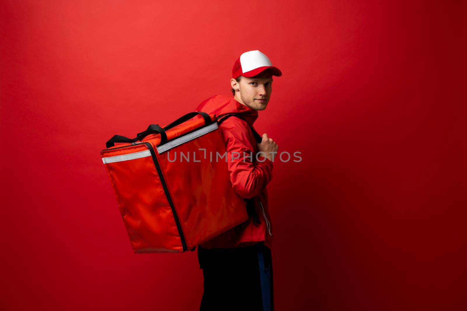 Delivery courier with red food backpack deliver food orders. Man delivering fast food with thermal backpack. Food delivery courier. by vovsht