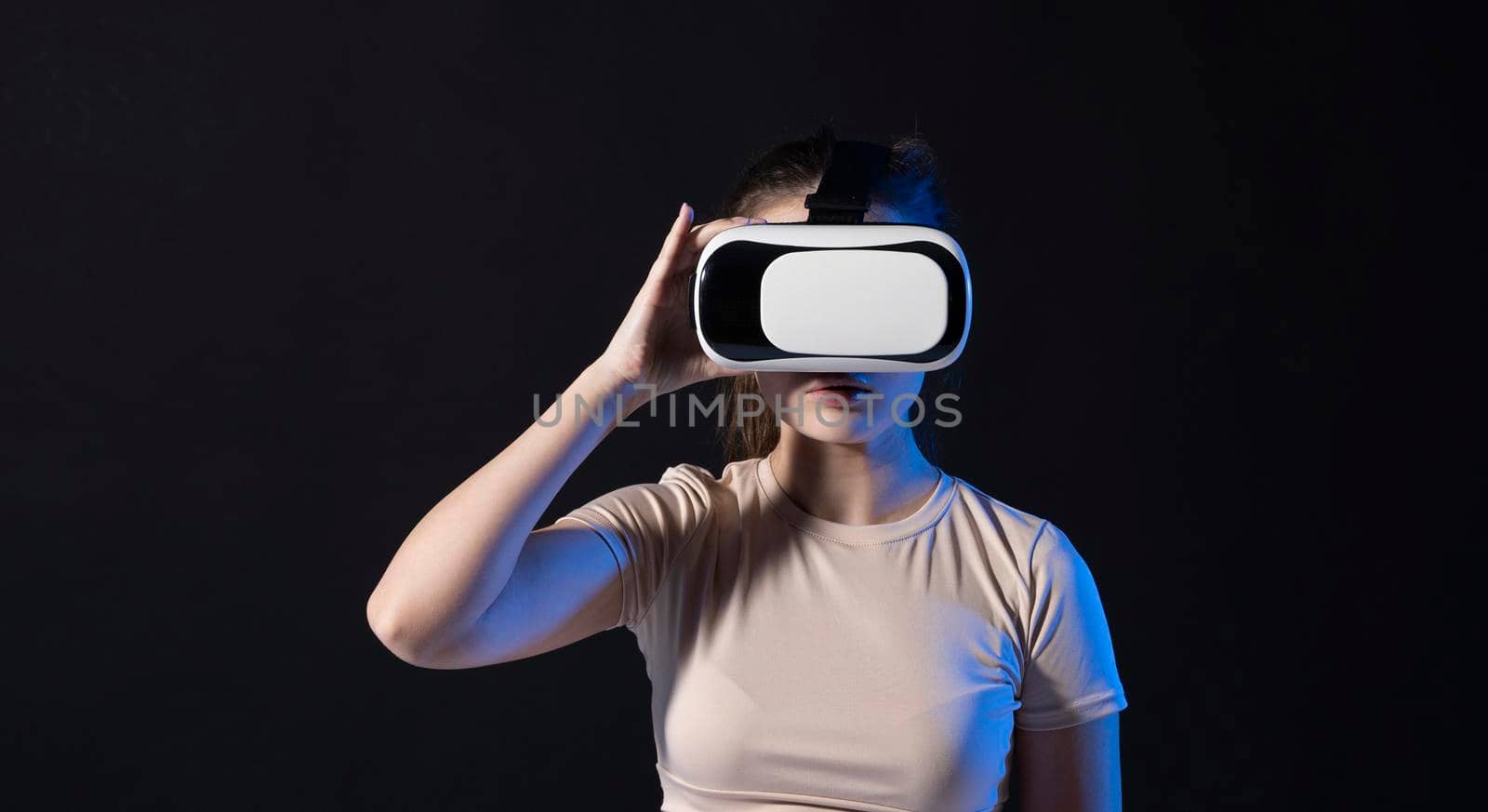 Young beautiful woman wearing a VR headset and experiencing a virtual reality simulation, metaverse and cyberspace concept