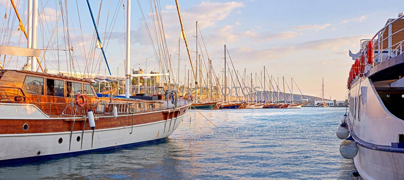 The marine harbor of Bodrum, Turkey. Scenic view of expensive yachts moored in Milta Marina. Closeup of boats and yachts docked at a port or pier during sunset on the water during a warm summer day.