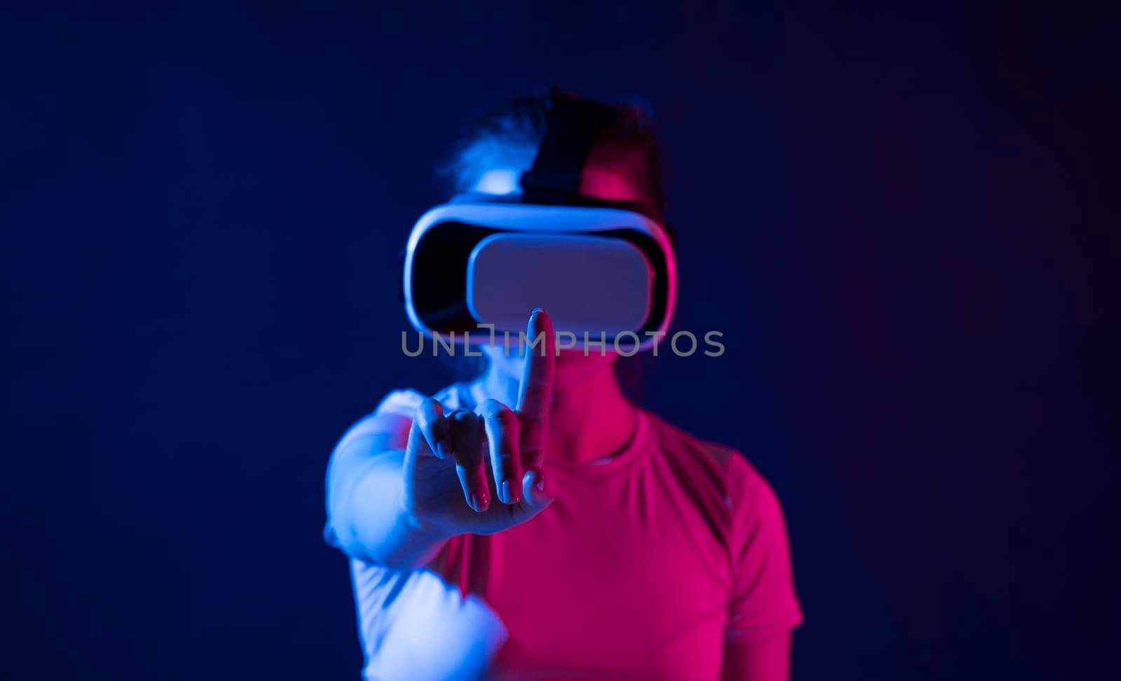 Metaverse technology concept. Woman with VR virtual reality goggles trying to touch something with a finger. Futuristic lifestyle