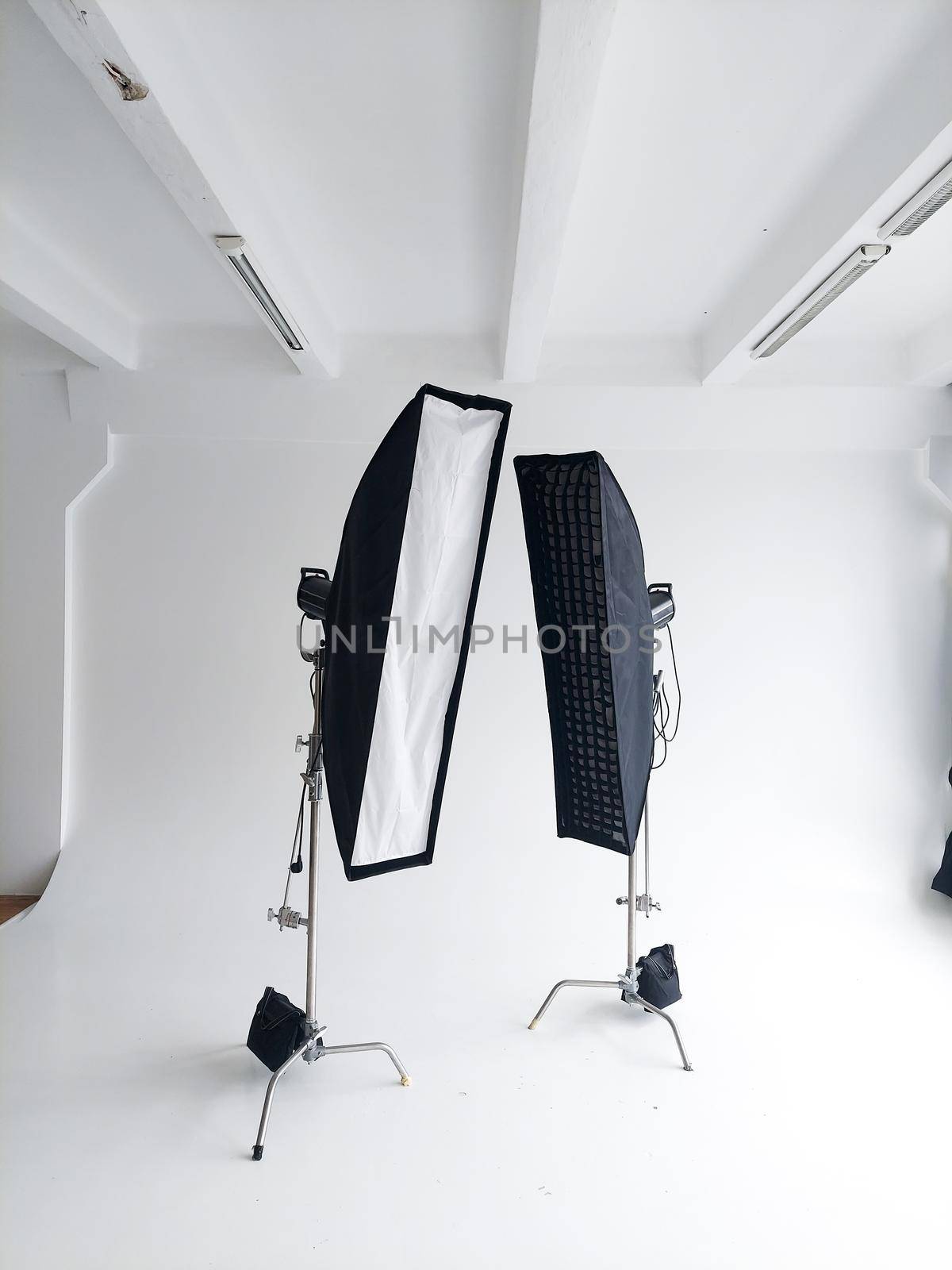 Lighting equipment on a cyclorama in modern photo studio. Two stripboxes on a c-stand on a clean white cyclorama background. Professional lighting equipment. by vovsht
