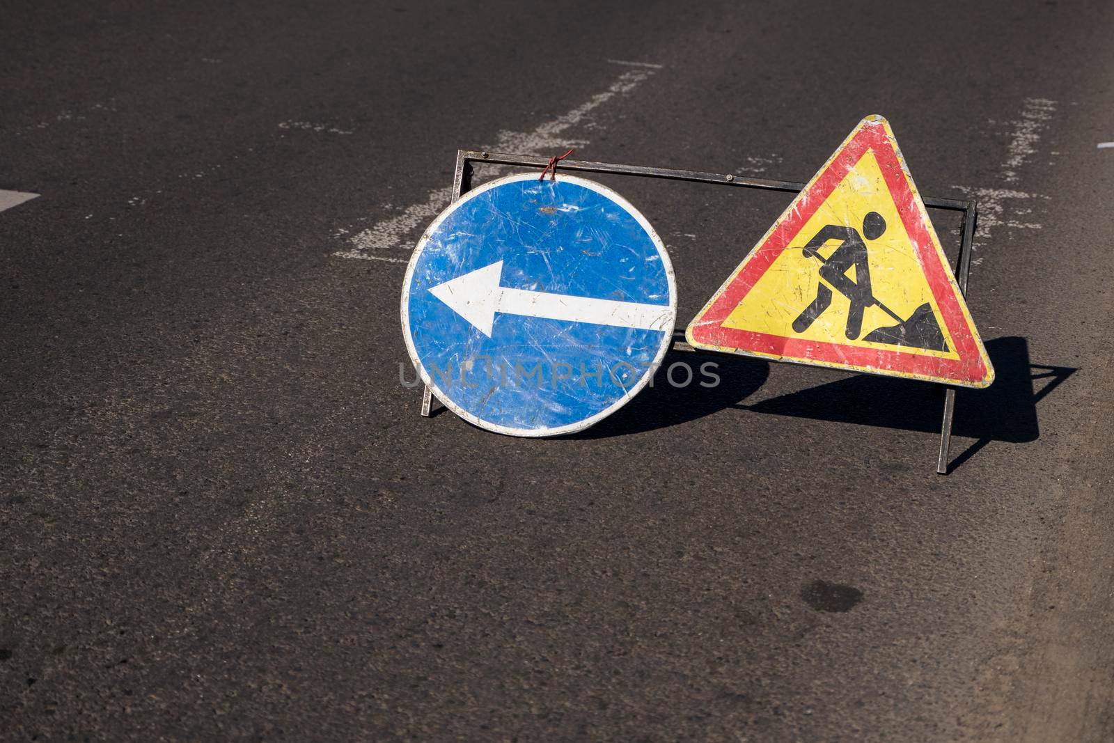 Blue and yellow-red safety signs warning about road works.The road is under construction or repair. Repair work in the middle of the carriageway, selective focus. by vovsht