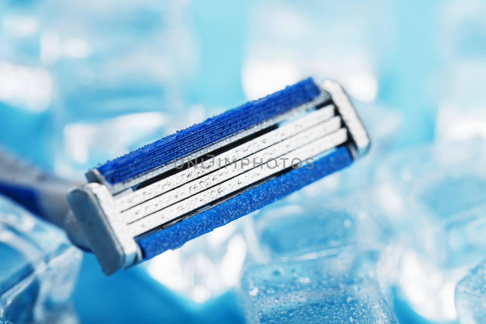 Shaving machine on a blue background with ice cubes. The concept of cleanliness and frosty freshness