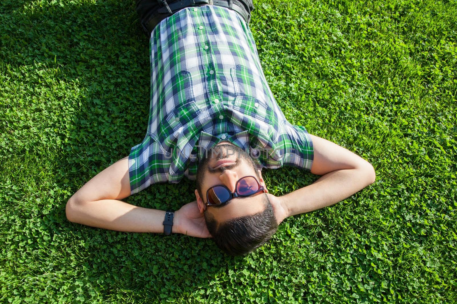 young man lie down on lawn and enjoying summertime. by Khosro1