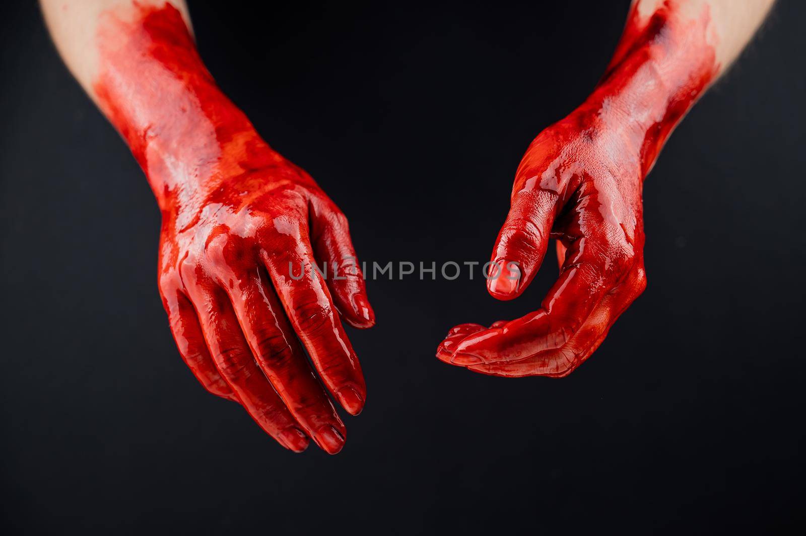 Women's hands in blood on a black background