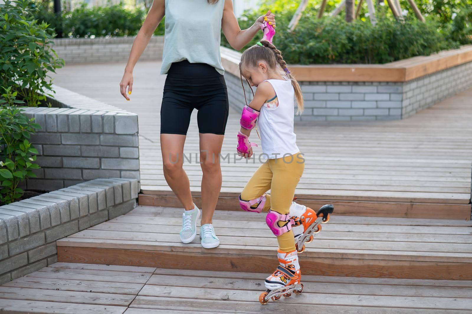 Caucasian woman teaches her daughter to skate on roller skates. by mrwed54