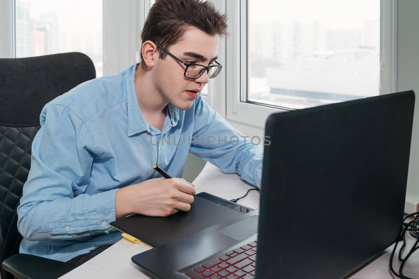 Man freelancer is working using laptop computer and graphics tablet at home office. Freelance lifestyle workplace