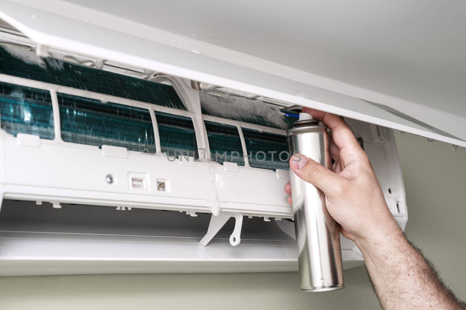 man master installer working and cleaning air filter on a indoor unit air conditioner at client's home with antibacterial spray.