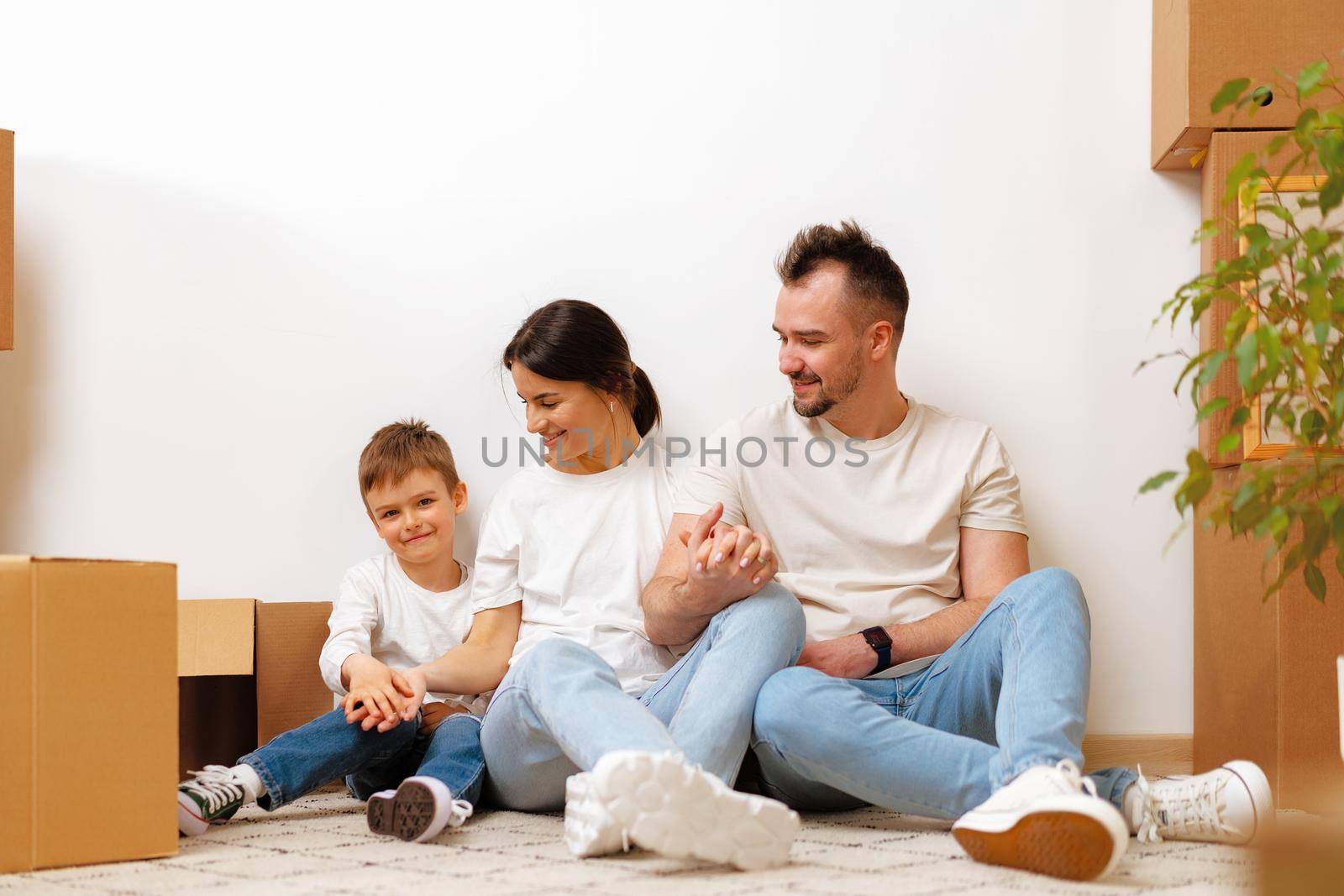 Young parents and son having fun during moving day to new house, portrait