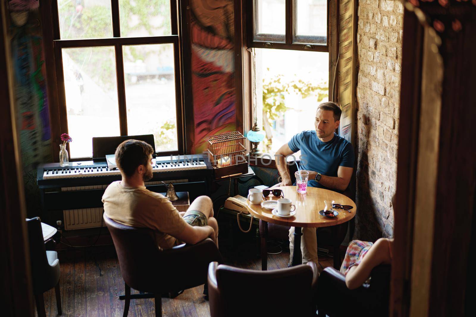 Two adult male friends sitting and talking in cafe, close up