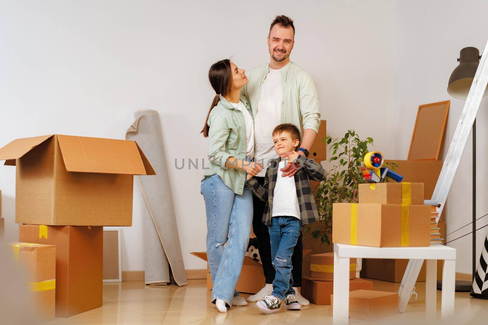 Young parents and son having fun during moving day to new house, portrait