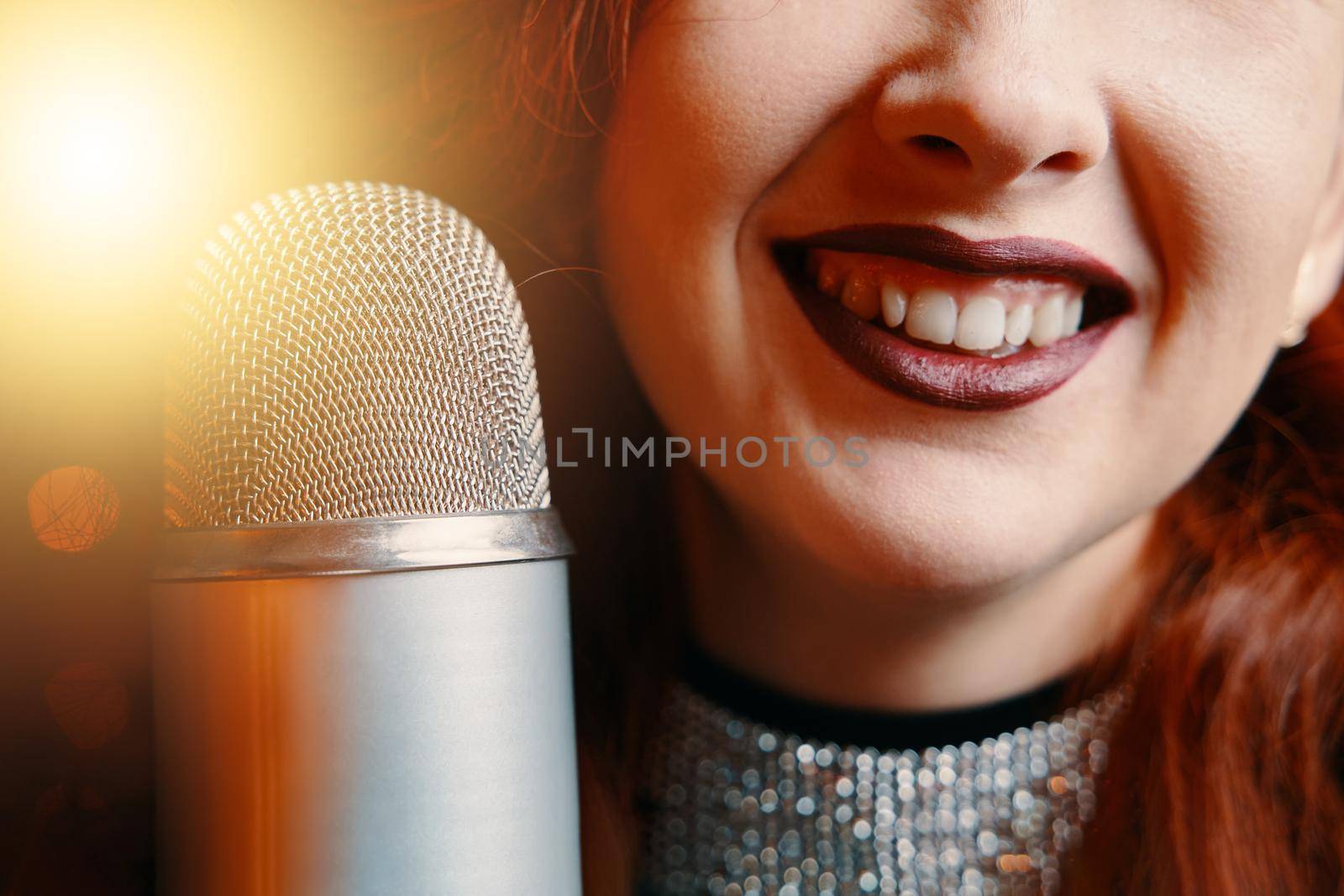 Smiling female singer's and retro microphone on bokeh blur background. by savconstantine