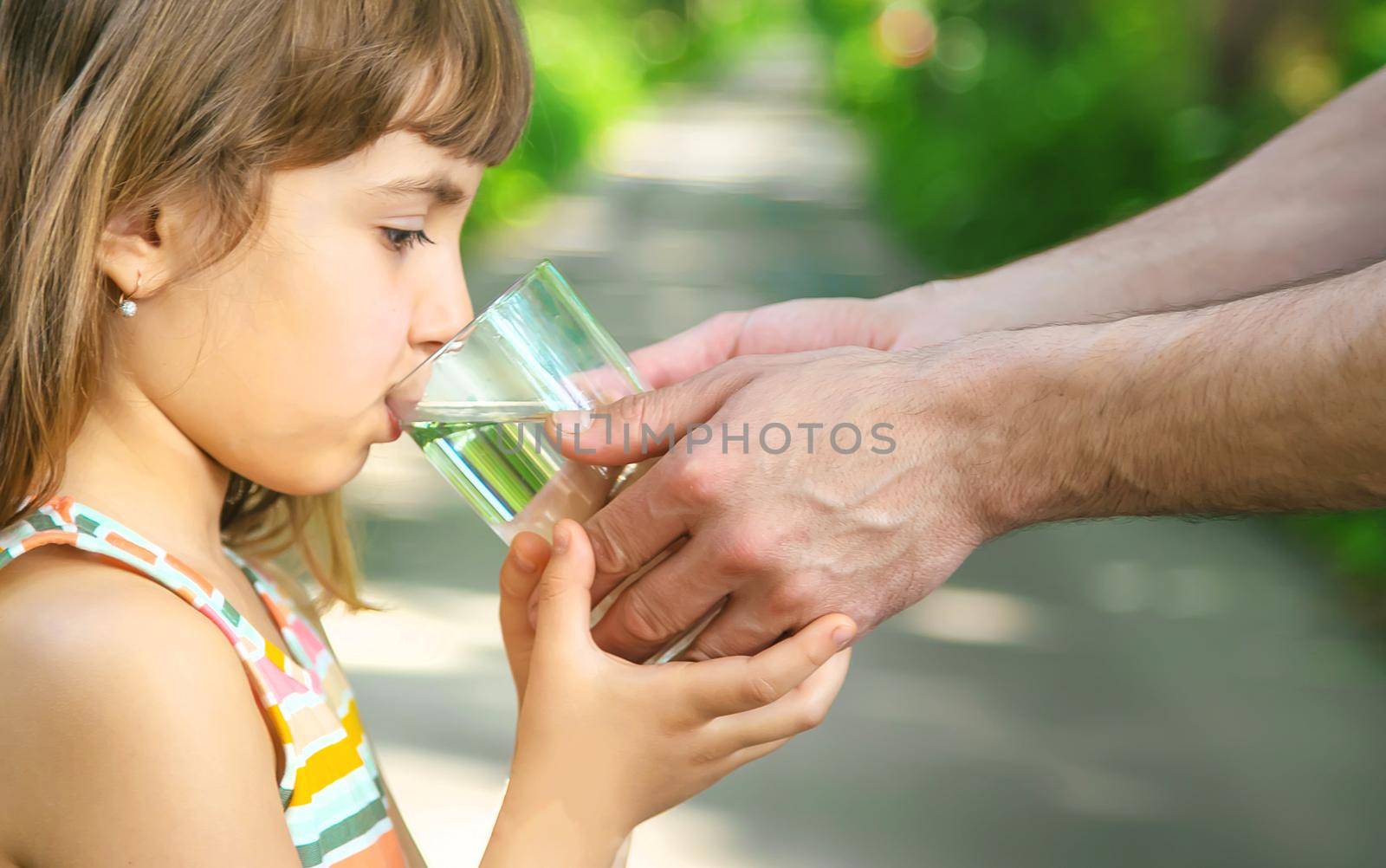 The father gives the child a glass of fresh water. Selective focus. by yanadjana