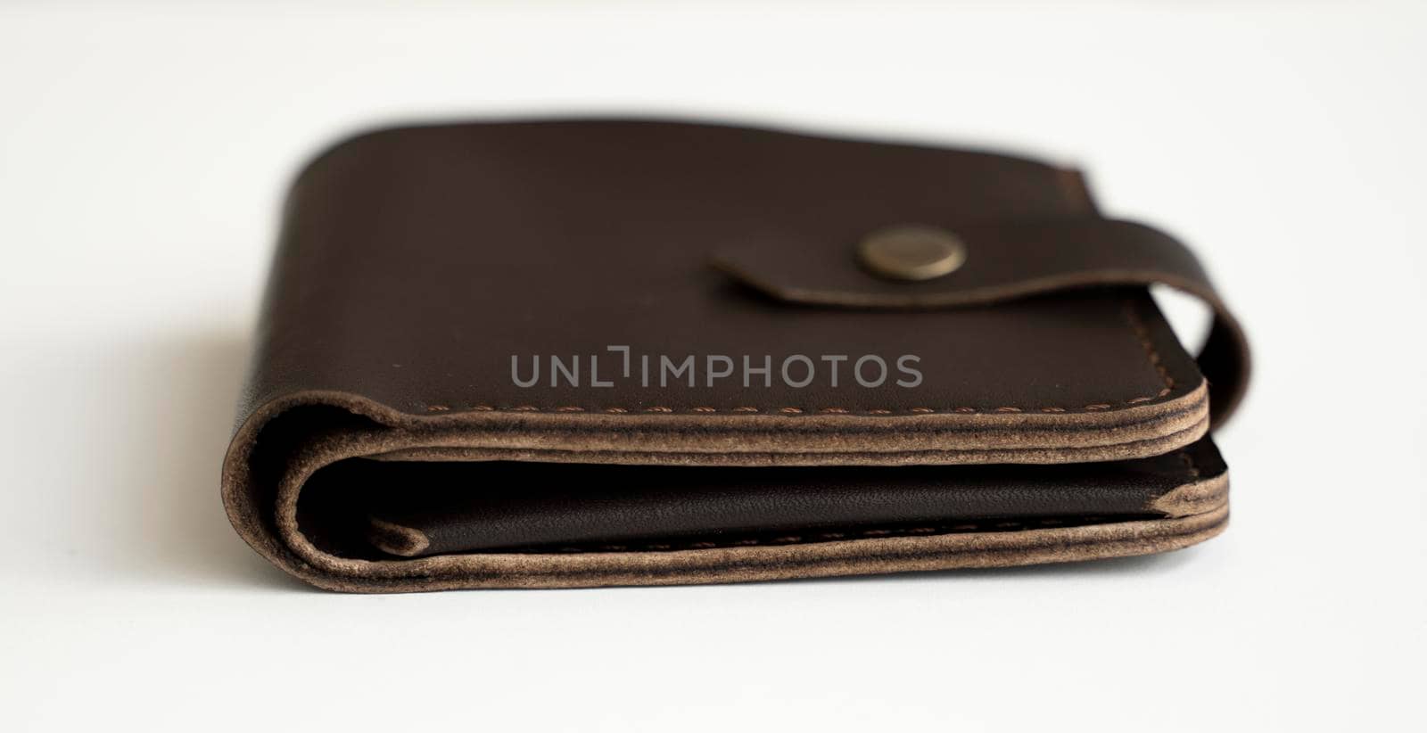 Side view of new dark brown genuine leather wallet with banknotes and credit card inside isolated on white background. by vovsht