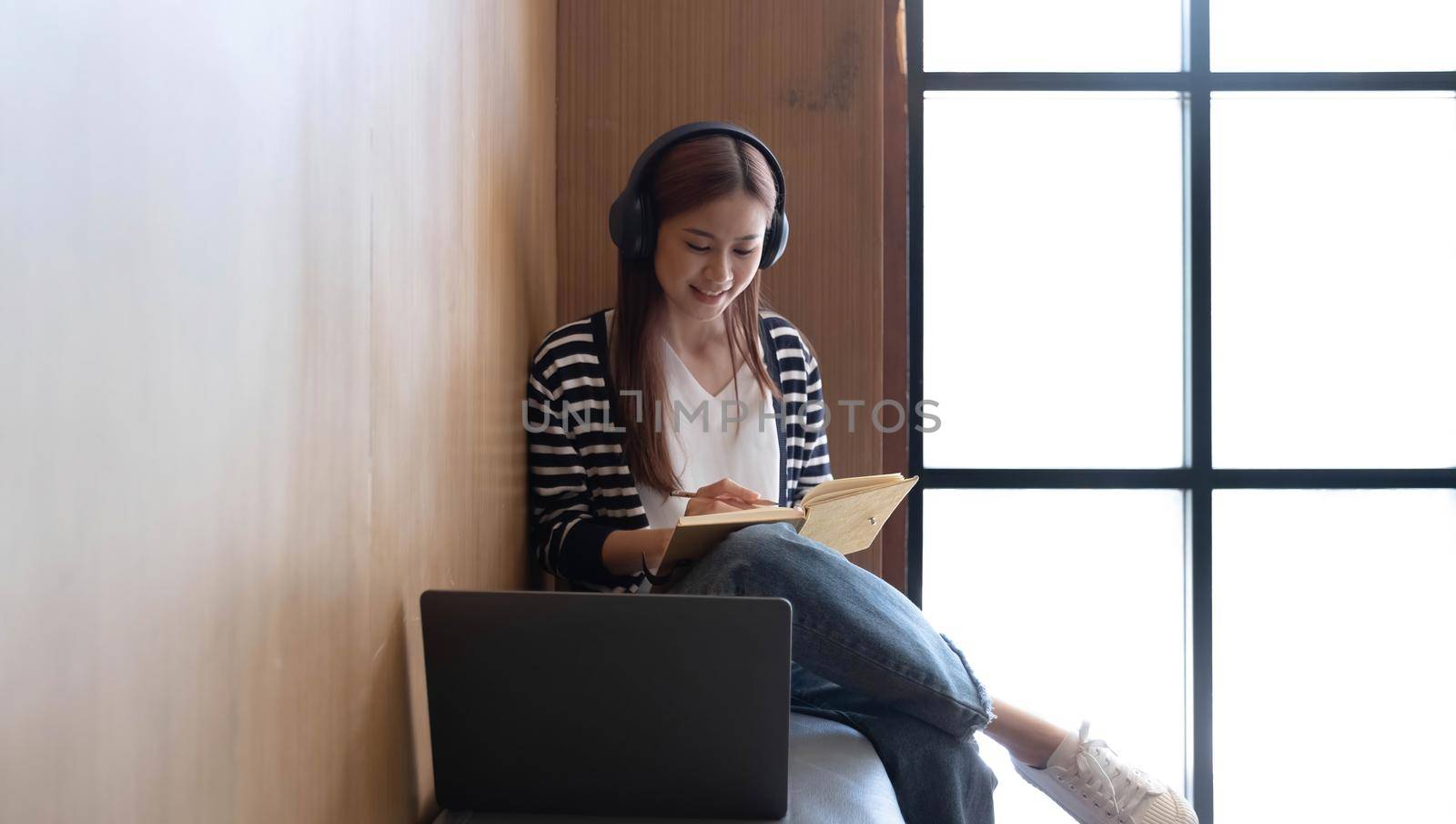 Young students use computers to study online. online education and learning Asian woman uses laptop technology while sitting at her desk and doing creative work. work from home concept by wichayada