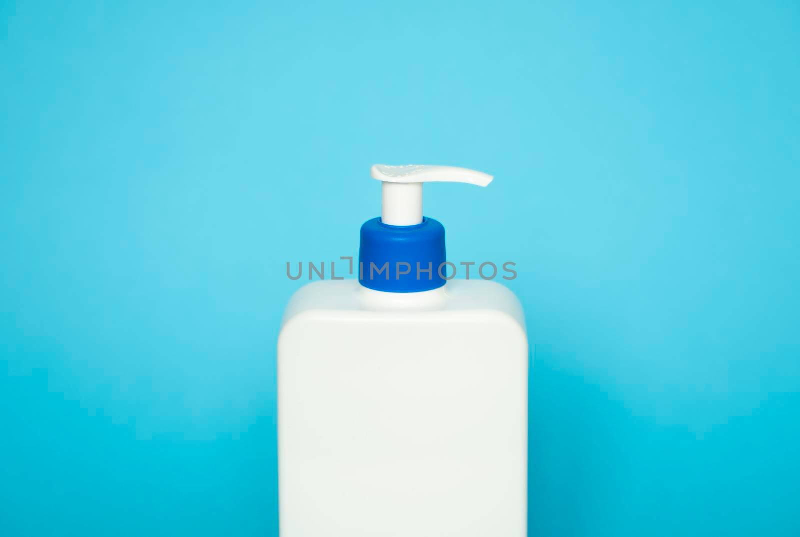 Large white cosmetic plastic bottle with pump dispenser pump and blue cap on blue background. Liquid container for gel, lotion, cream, shampoo, bath foam