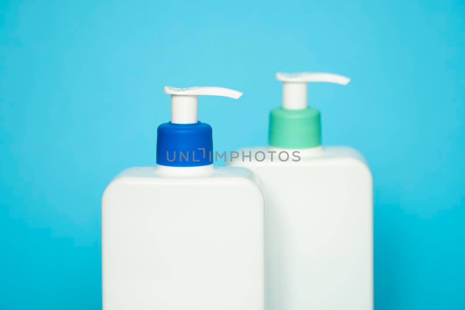 Shampoo or hair conditioner bottles with dispenser pump on blue background