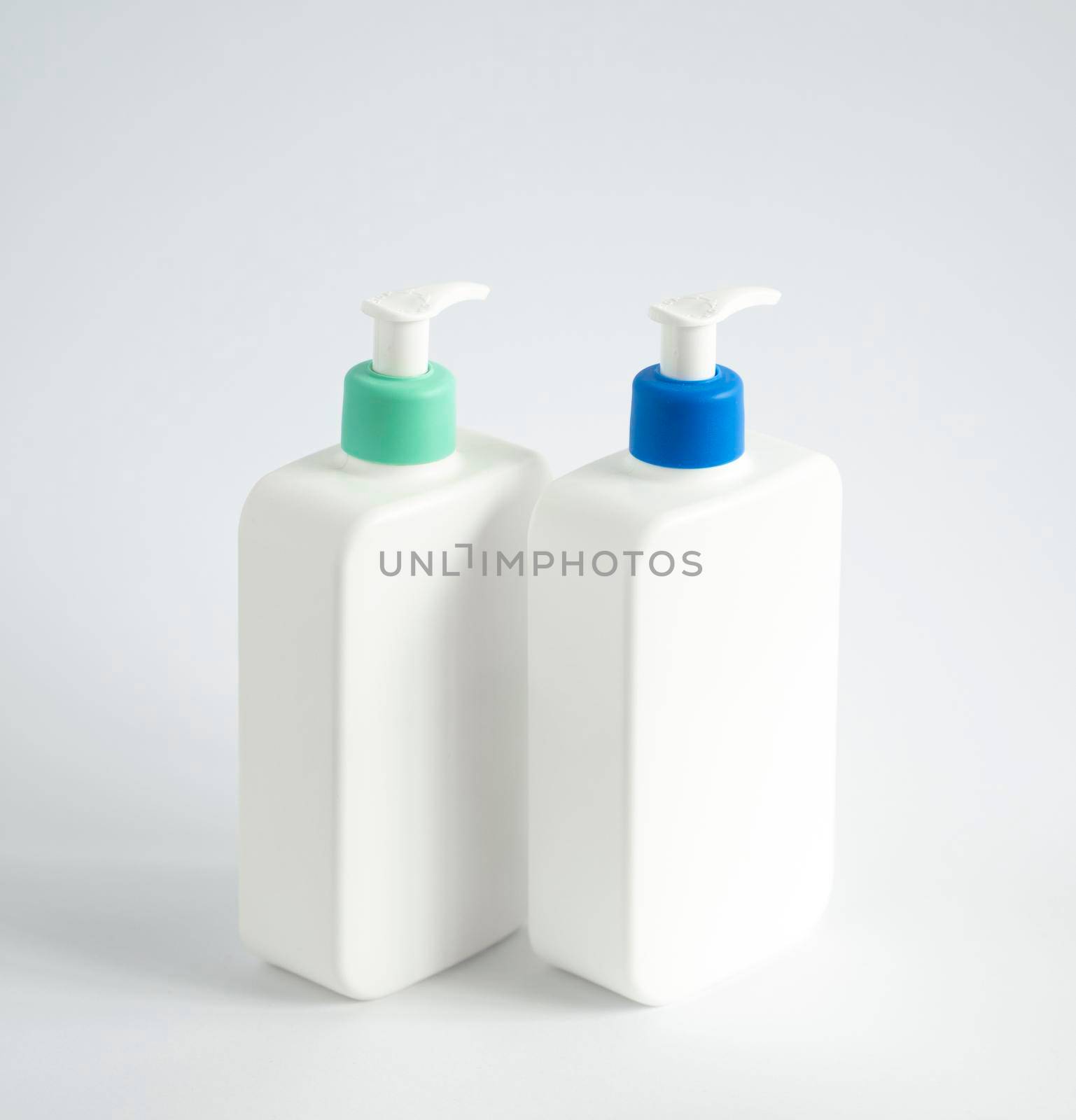Two liquid containers for gel, lotion, cream, shampoo, bath foam. Cosmetic plastic bottle with dispenser pump on white background. Cosmetic packaging mockup with copy space. by vovsht