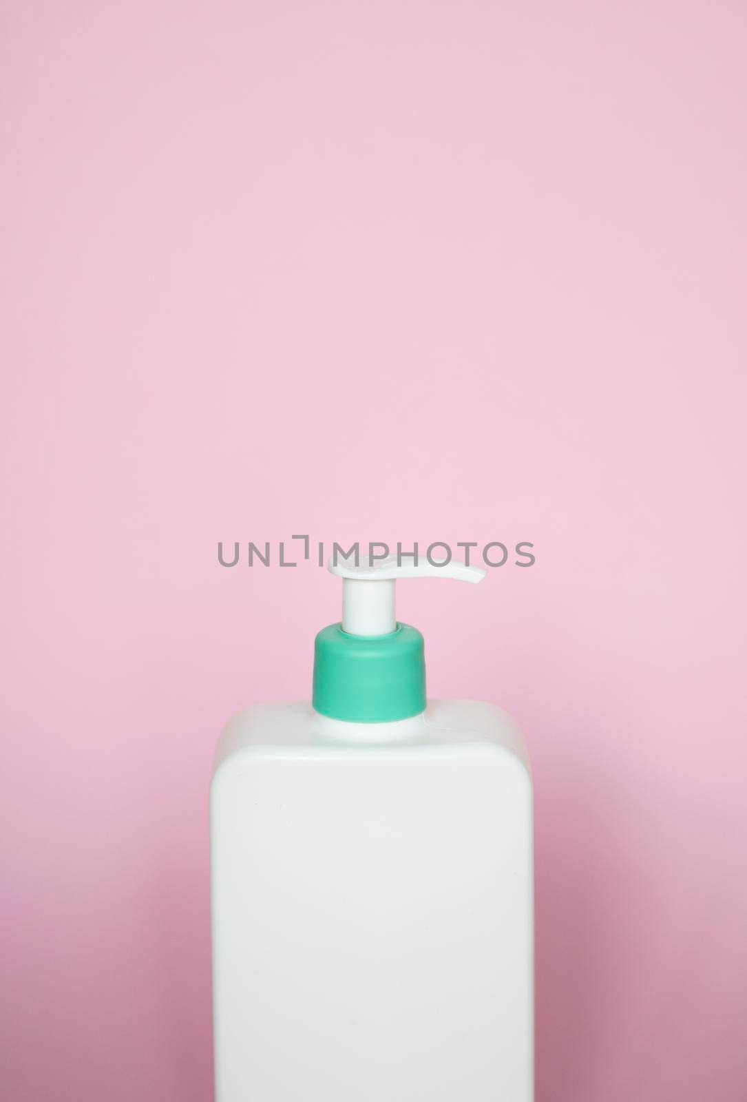 Large white cosmetic plastic bottle with pump dispenser pump and green cap on pink background. Liquid container for gel, lotion, cream, shampoo, bath foam
