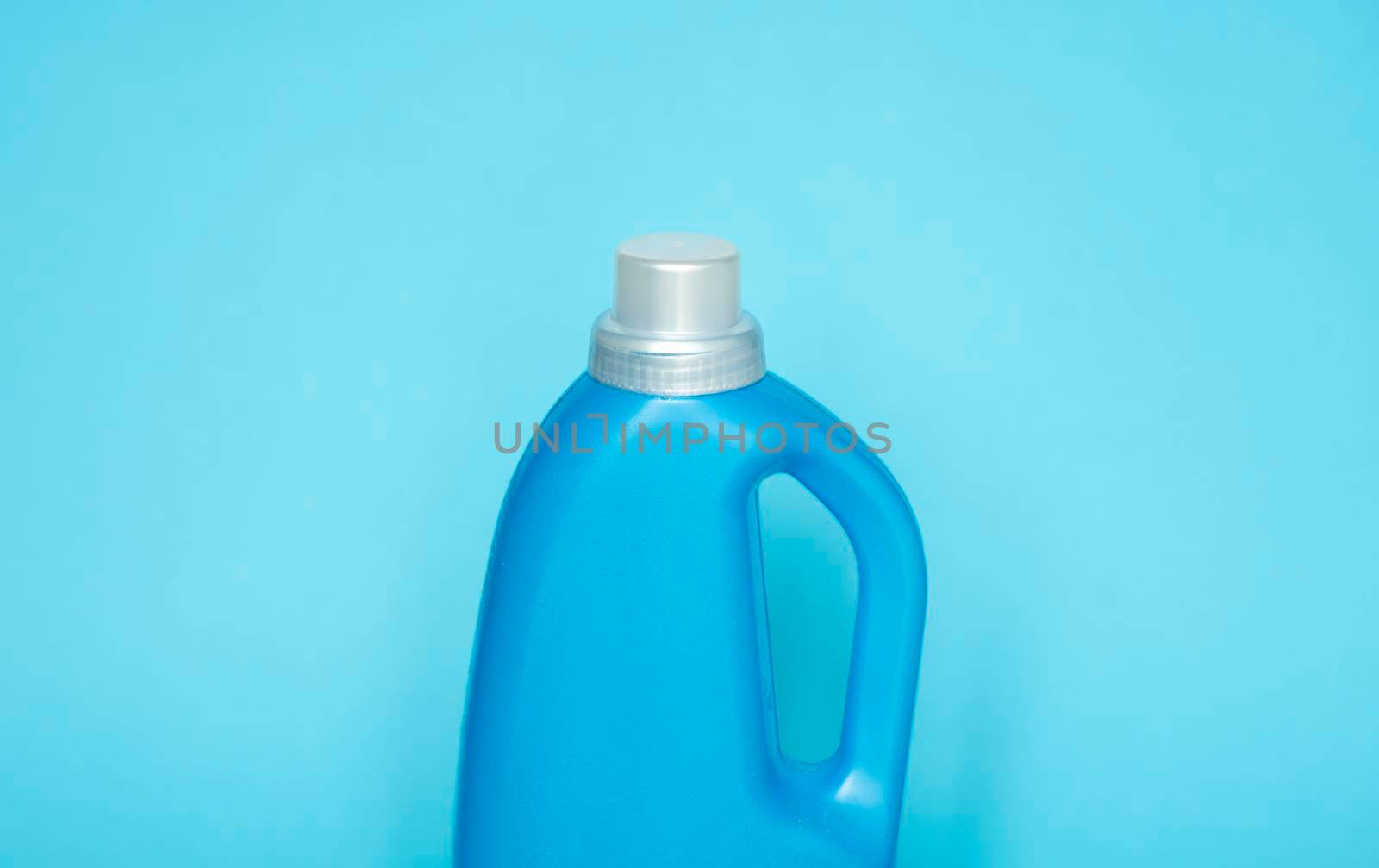 Blue plastic bottle stands on blue background. Conditioner or liquid powder for washing. Capacity with space for copying. Layout for logo application. by vovsht