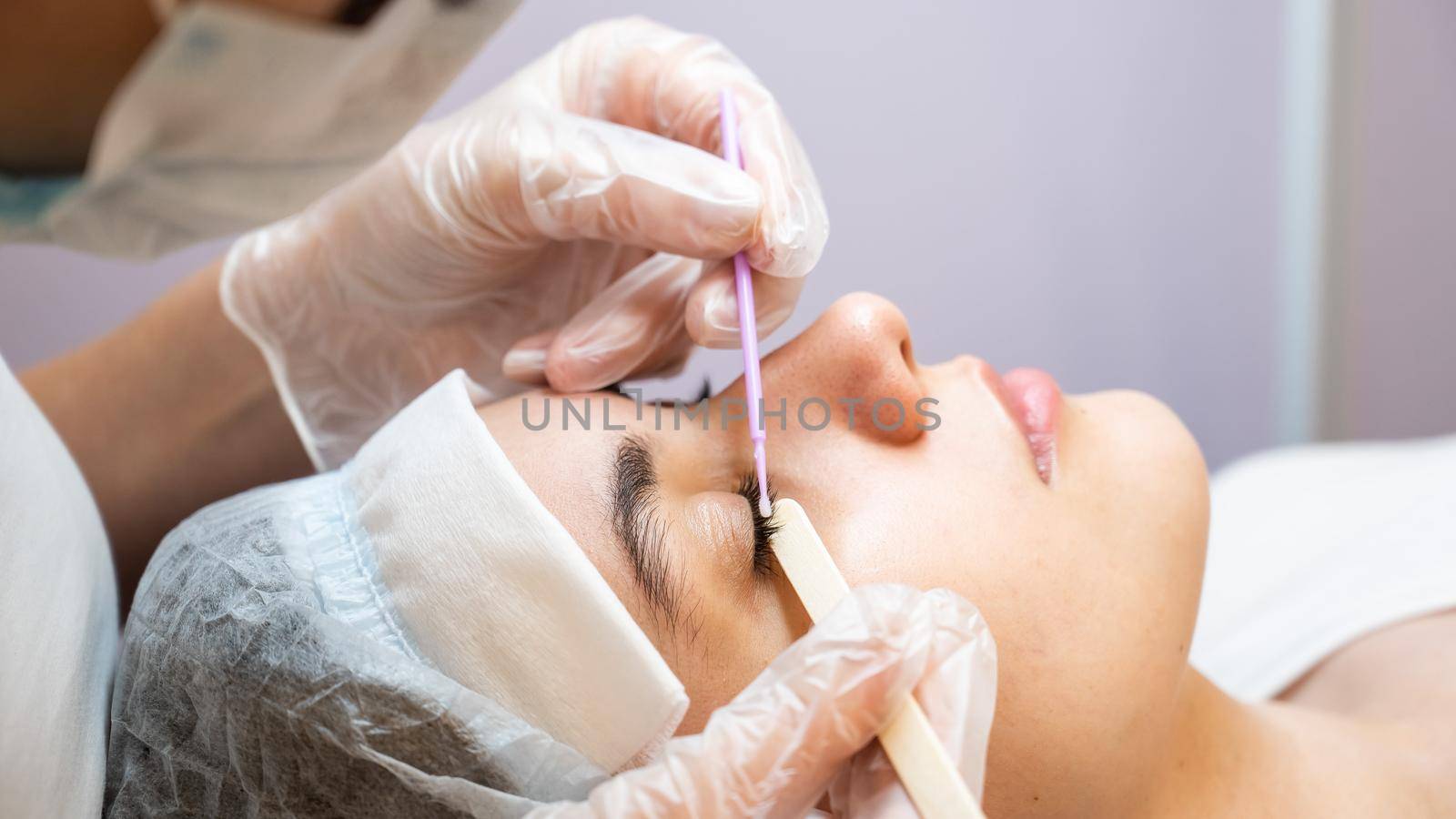 The master cleans the eyelashes of a woman preparing before lamination