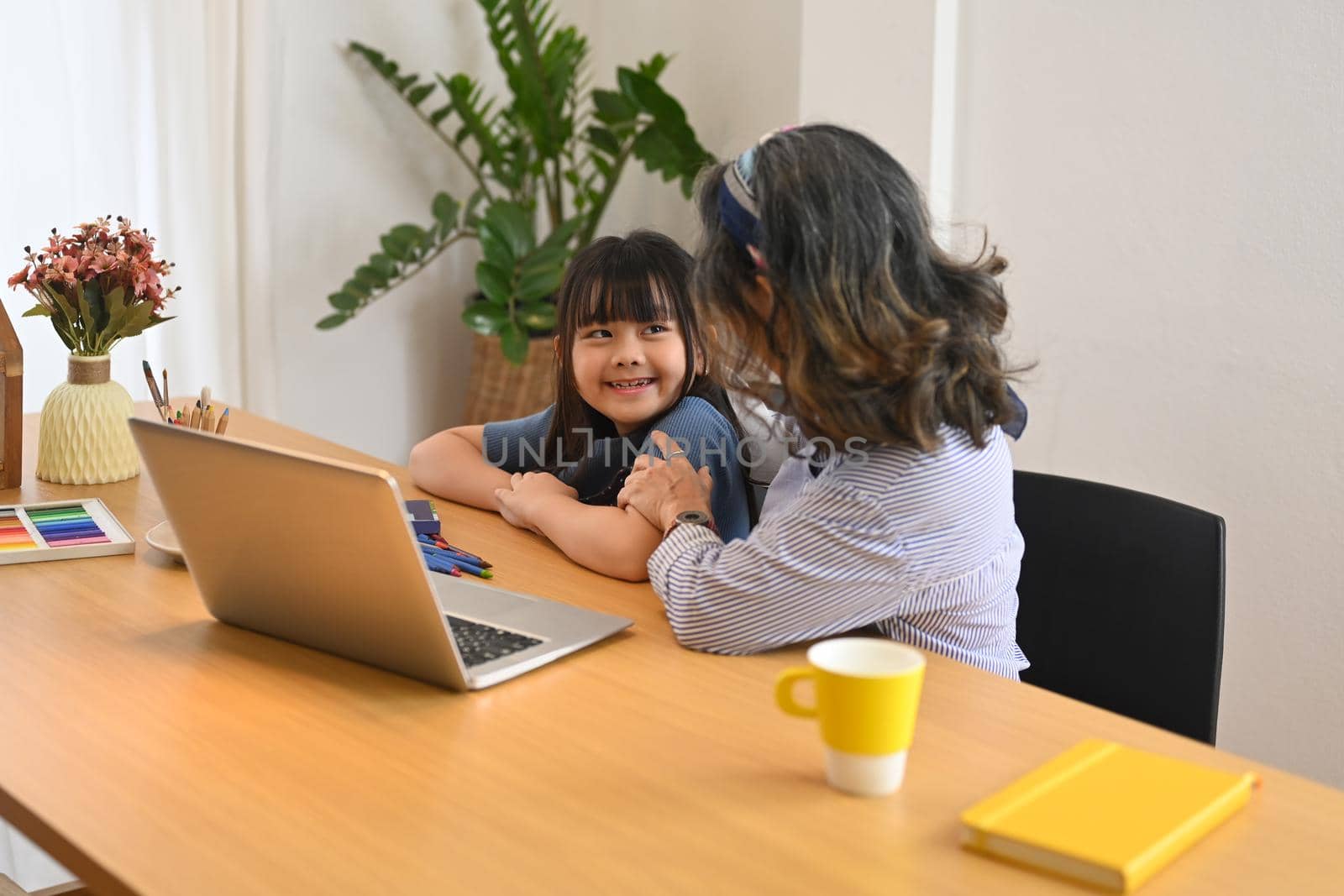 Adorable little asian girl using laptop with grandmother in living room. Multi generational, family and love concept.