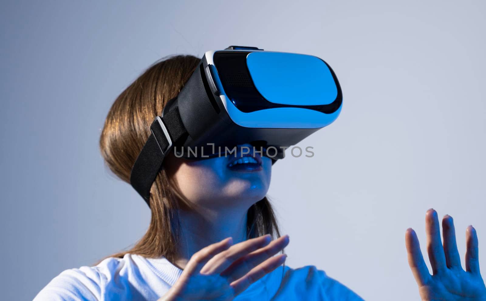 Young brunette woman wearing a virtual reality headset goggles and playing a game with a friends in metaverse. Future technology concept