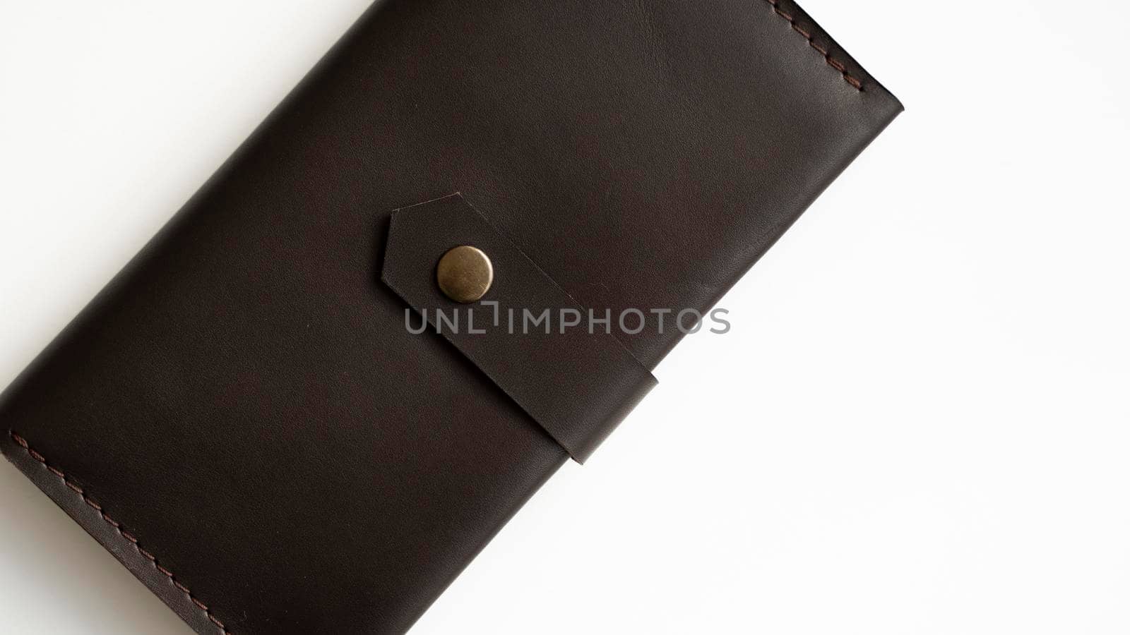 Top view of new dark brown genuine leather wallet with banknotes and credit card inside isolated on white background