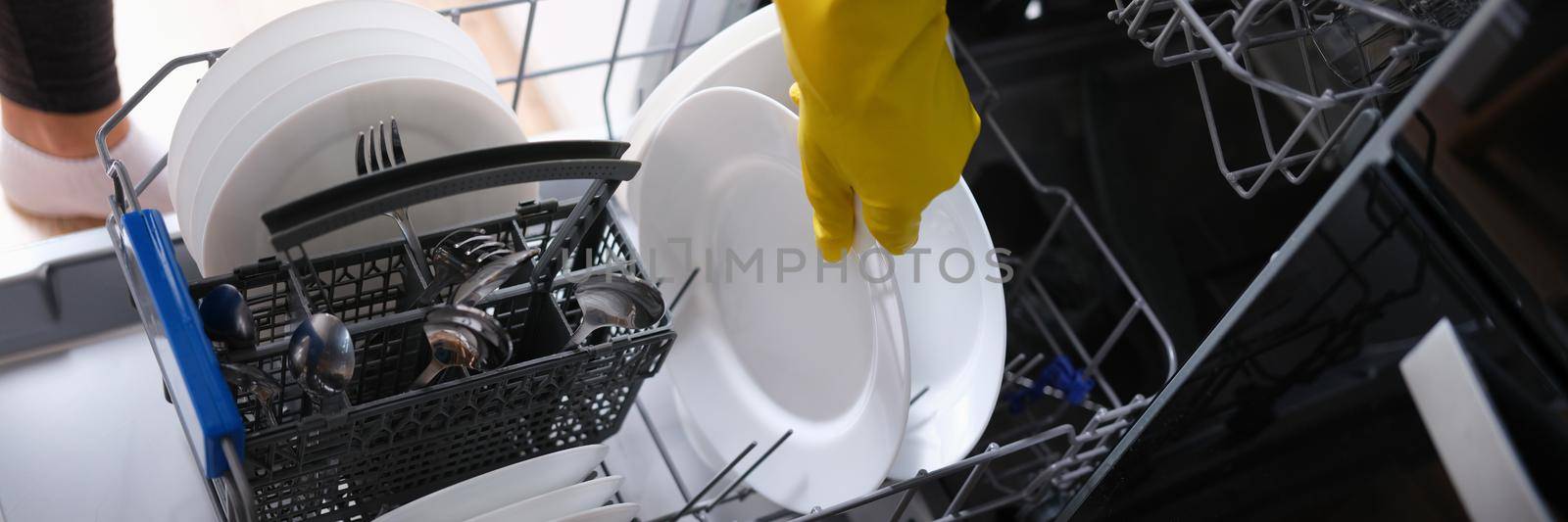 A woman takes out clean dishes from the dishwasher, close-up. Cutlery washing, household appliances, housework