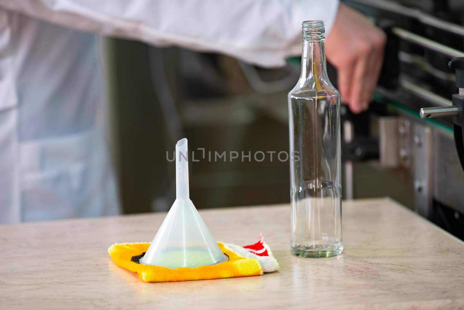 Worker hands and empty bottles on a conveyor belt in the production of alcoholic beverages.