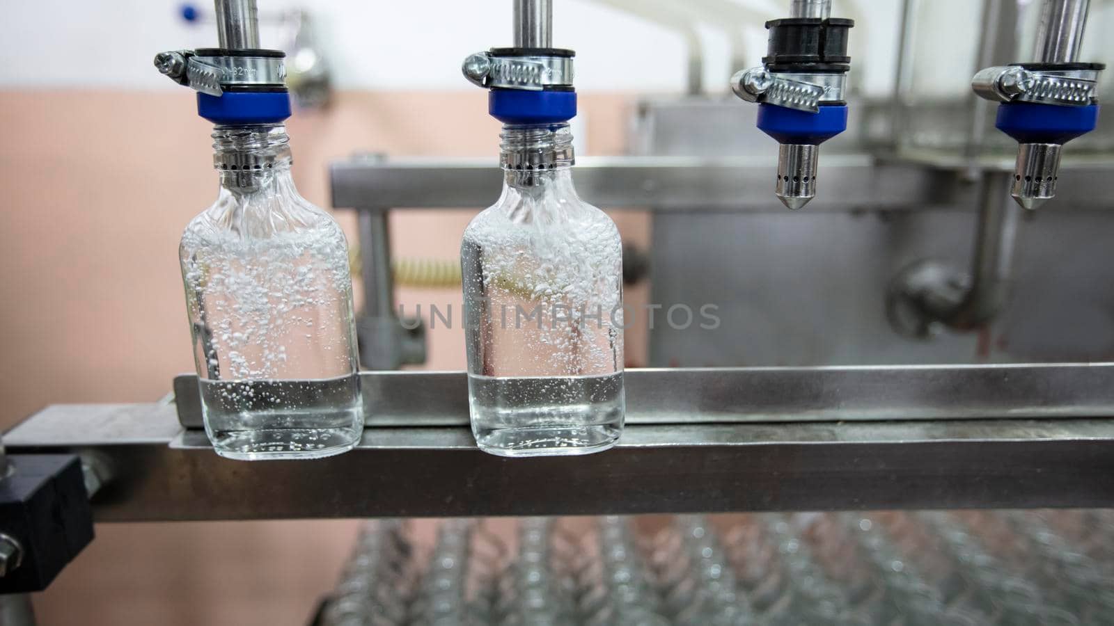 A row of glass bottles on a conveyor belt for the production of alcoholic beverages.