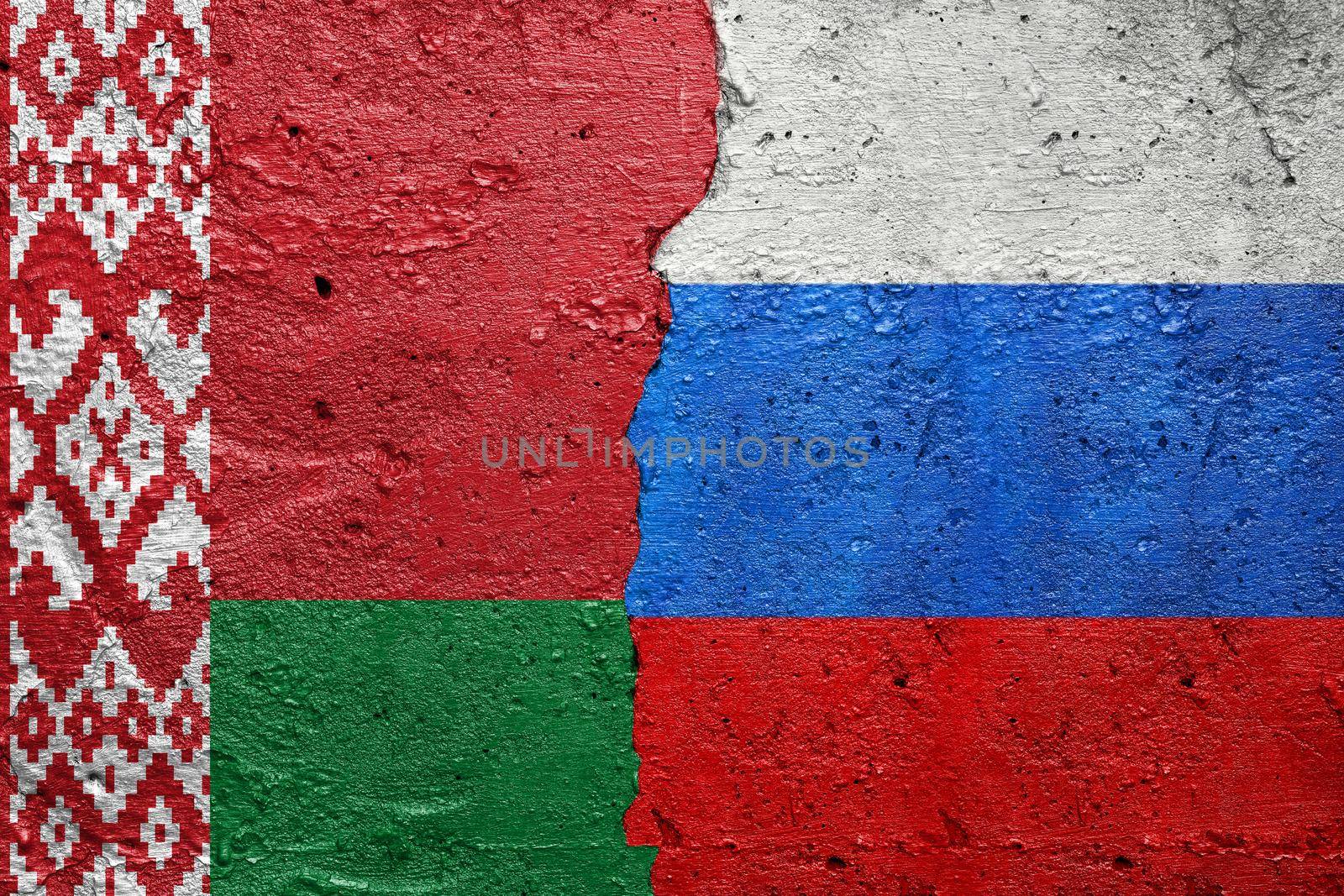 Belarus and Russia - Cracked concrete wall painted with a Belarusian flag on the left and a Russian flag on the right