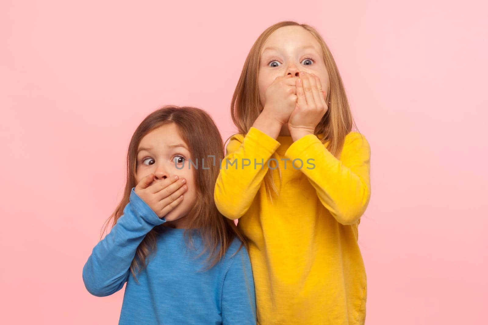 Portrait of two little frightened girls covering mouth with hands and looking with scared eyes by Khosro1