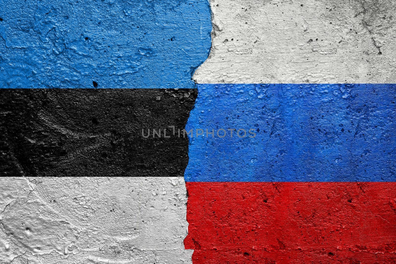 Estonia vs Russia - Cracked concrete wall painted with a Estonian flag on the left and a Russian flag on the right