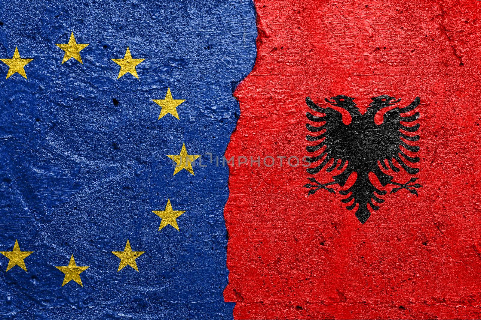 European Union and Albany - Cracked concrete wall painted with a EU flag on the left and a Albanian flag on the right stock photo by adamr