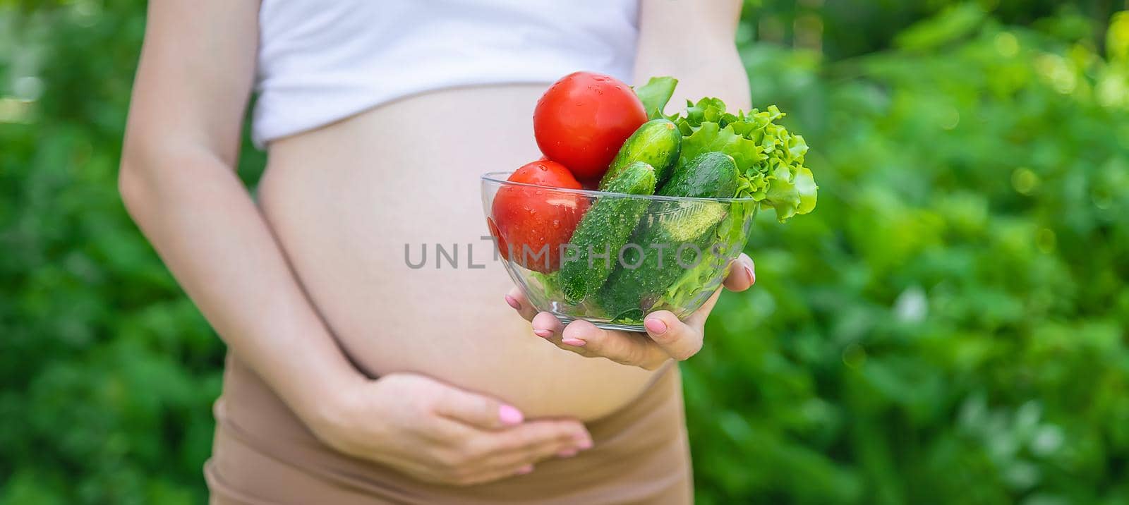 A pregnant woman with vegetables in her hands. Selective focus. by yanadjana