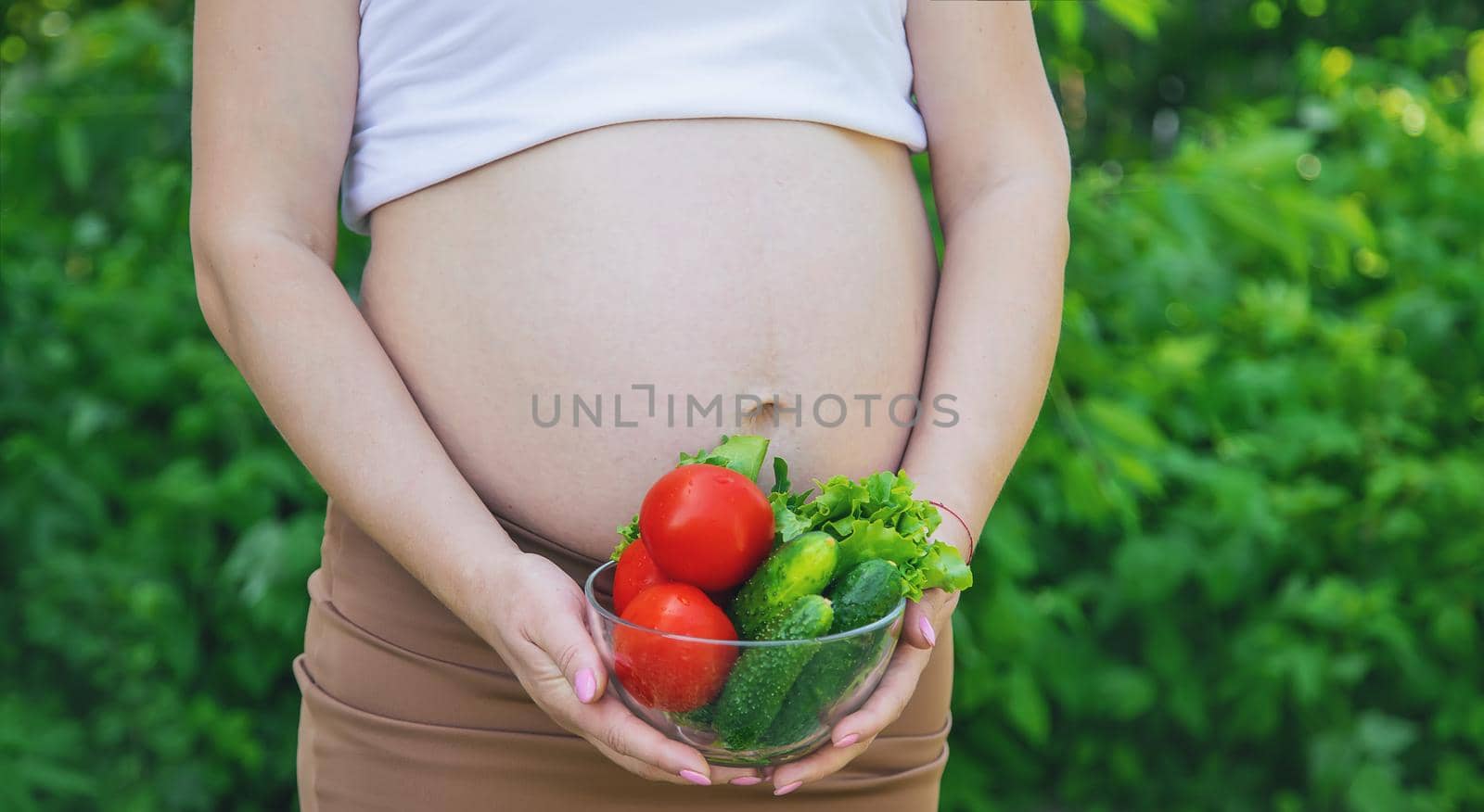 A pregnant woman with vegetables in her hands. Selective focus. by yanadjana