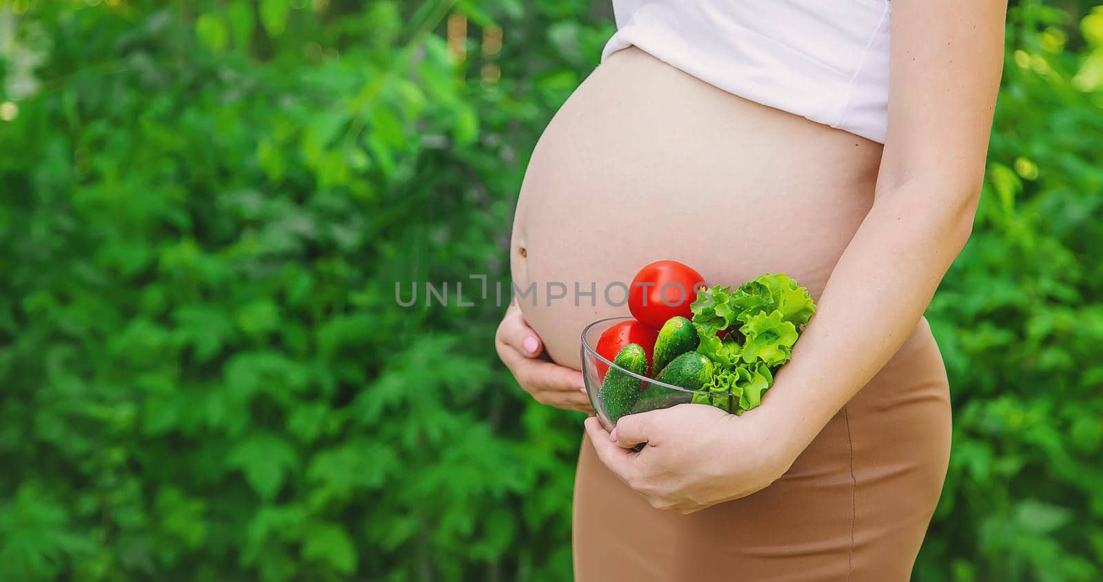 A pregnant woman with vegetables in her hands. Selective focus. food.